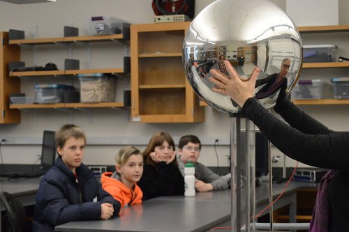 Professor holding metal sphere for sixth graders