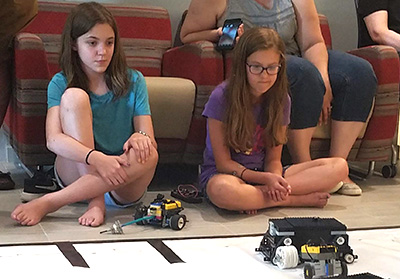 Two girls observing robots
