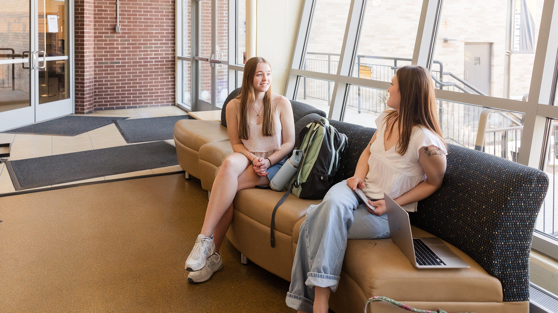 MCLA campus two students sitting on a sofa in a hallway
